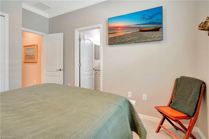 Carpeted bedroom with ensuite bathroom and crown molding