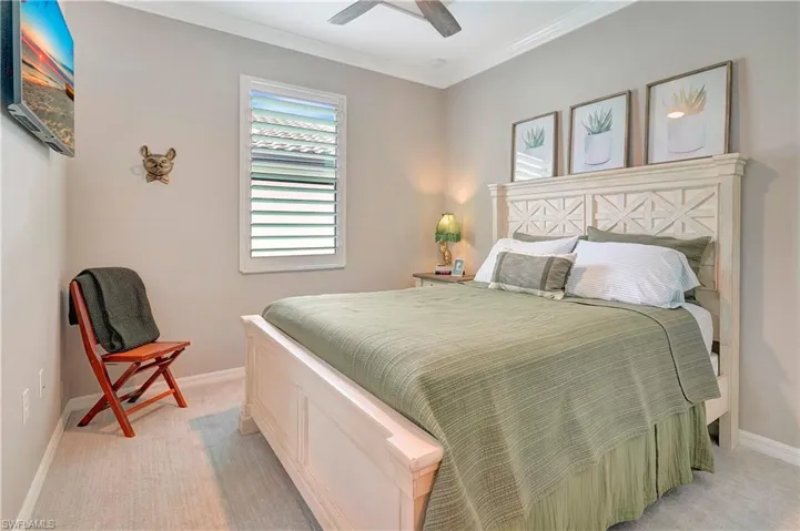 Bedroom with light carpet, ceiling fan, and ornamental molding