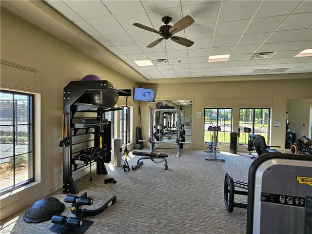 Workout area featuring carpet flooring, ceiling fan, and a paneled ceiling