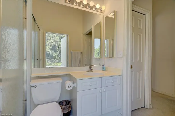 Bathroom featuring a shower with shower door, vanity, and toilet