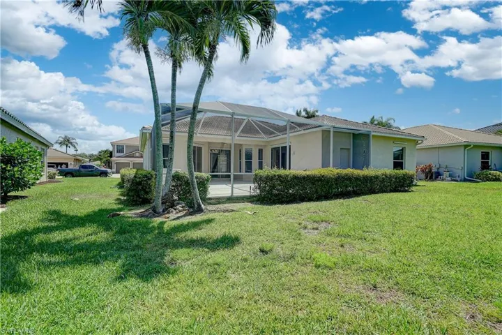 Back of property featuring a lanai and a yard