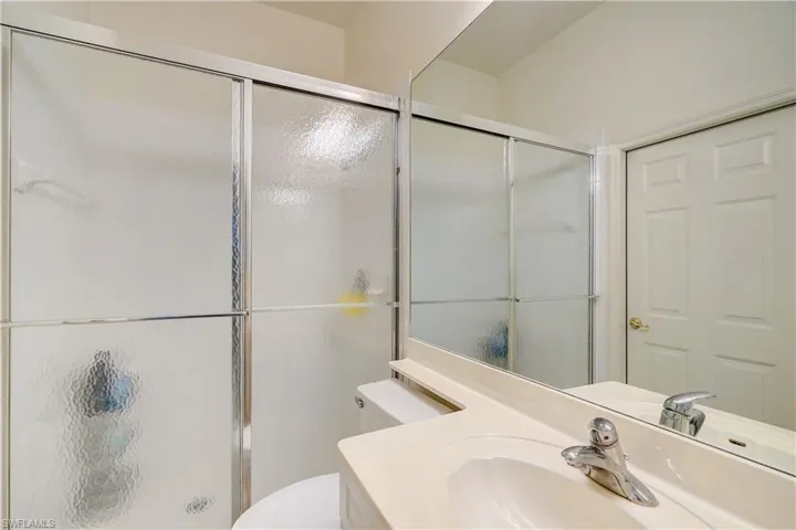 Bathroom featuring sink, an enclosed shower, and toilet