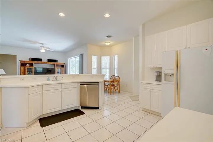 Kitchen with white refrigerator with ice dispenser, white cabinets, and stainless steel dishwasher