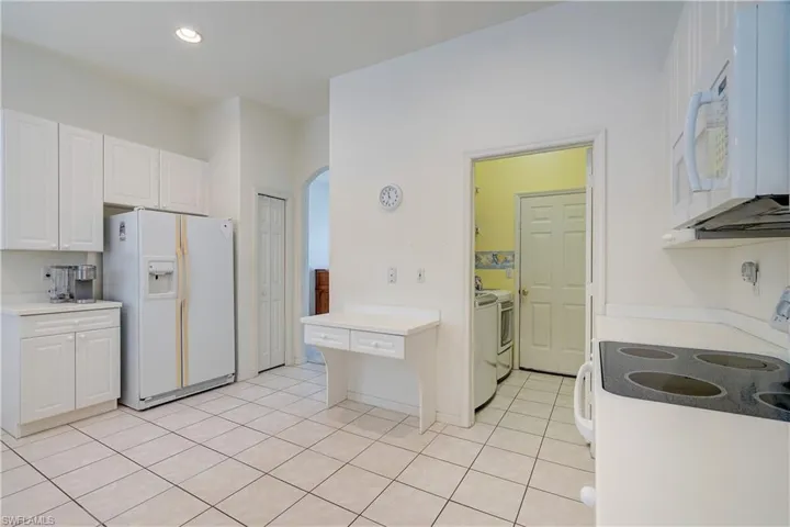 Kitchen featuring white cabinets, white appliances, and light tile floors