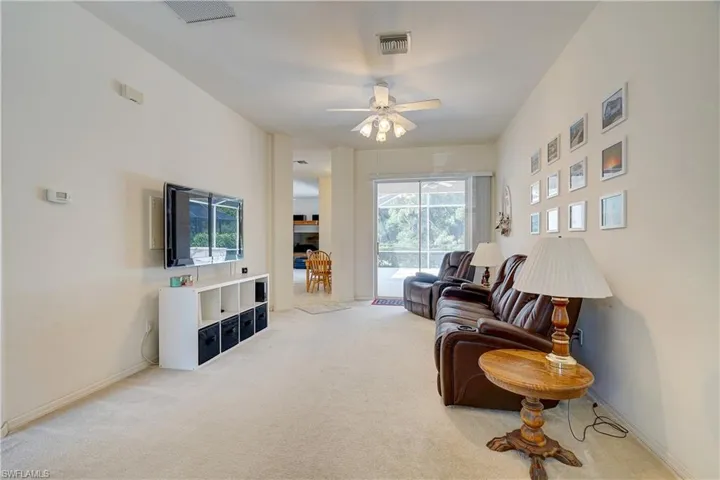 Living room featuring light colored carpet, plenty of natural light, and ceiling fan