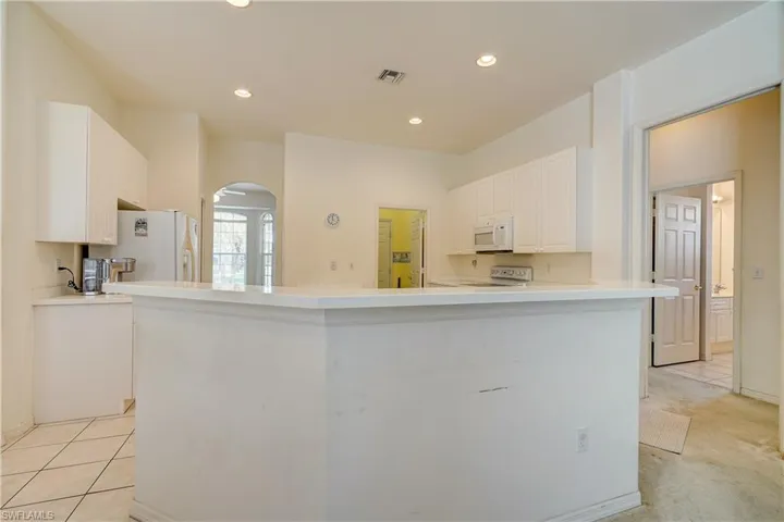 Kitchen featuring white appliances, white cabinets, and light colored carpet