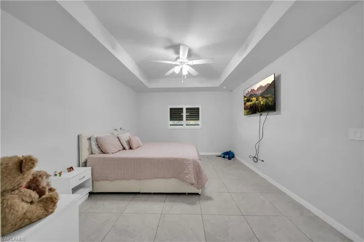 Bedroom featuring a ceiling fan, a raised ceiling, and light tile patterned flooring