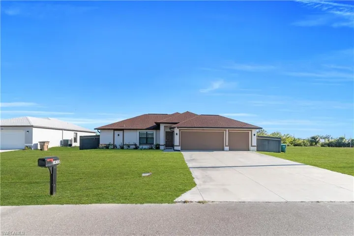 Prairie-style house featuring a front lawn, a garage, concrete driveway, roof with shingles, and stucco siding