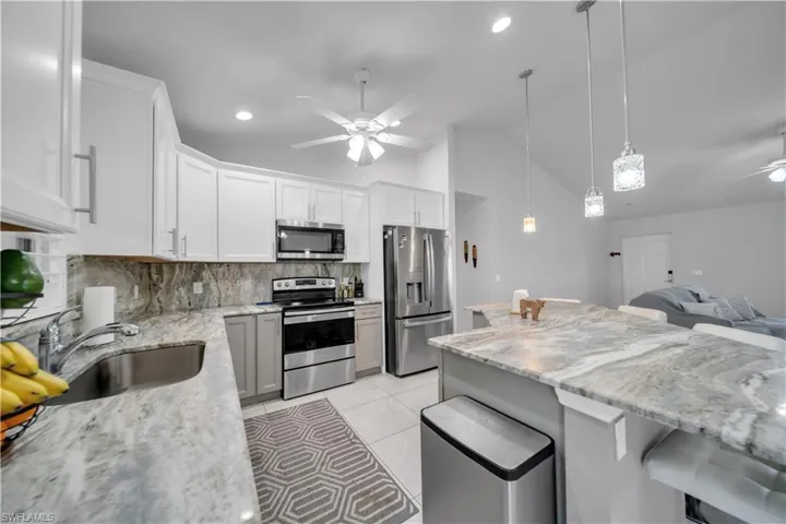 Kitchen featuring a ceiling fan, stainless steel appliances, a breakfast bar, pendant lighting, and open floor plan