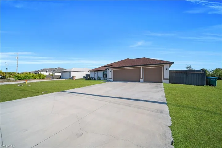 View of front of house with a front lawn, concrete driveway, a garage, and stucco siding