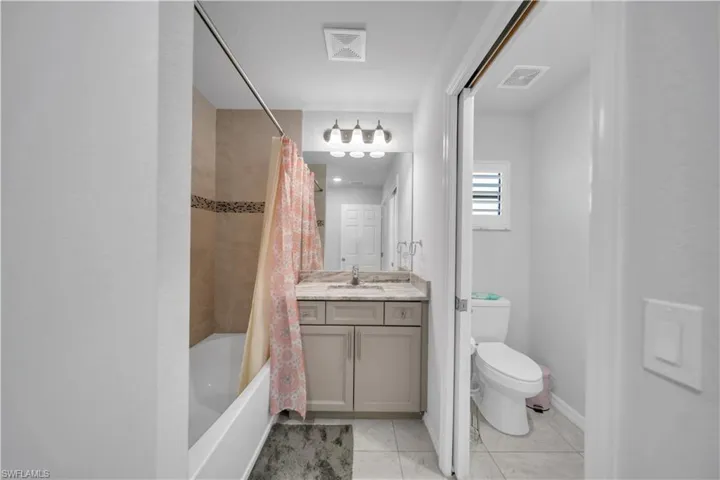 Full bathroom with vanity, shower / tub combo with curtain, and light tile patterned floors