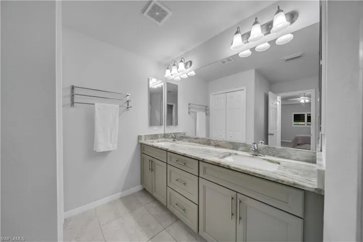 Bathroom featuring double vanity, a ceiling fan, and a closet