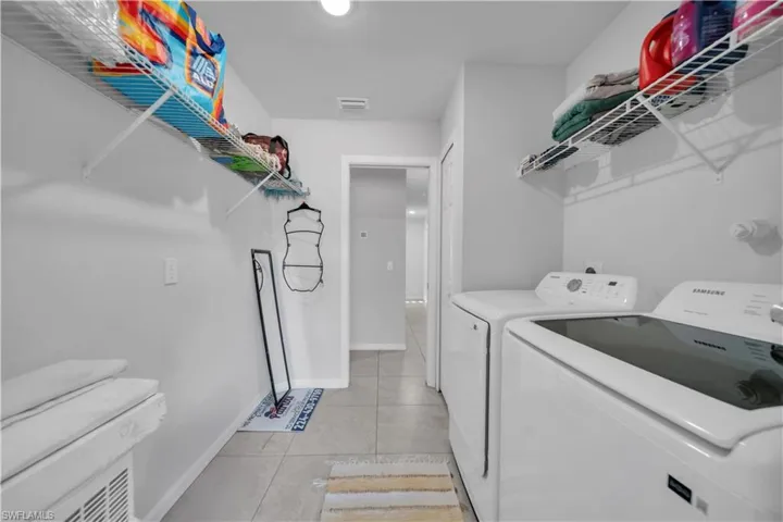 Laundry room featuring light tile patterned floors and washer and clothes dryer