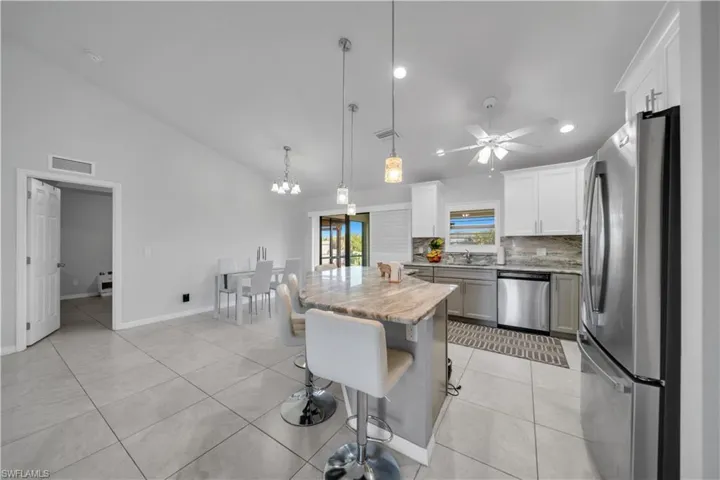 Kitchen featuring stainless steel appliances, a kitchen breakfast bar, a ceiling fan, a center island, and light tile patterned floors