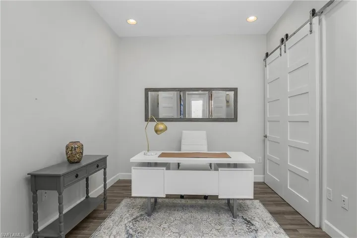 Office space featuring a barn door (closet), Tile-wood-type flooring, and recessed lighting