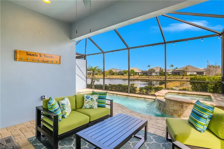 View of patio / terrace featuring a sunroom, glass enclosure, a residential view, a pool with connected hot tub, and a water view