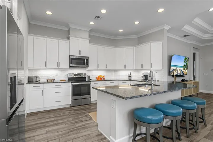 Kitchen featuring a breakfast bar, a peninsula, ornamental molding, stainless steel appliances, and dark stone countertops