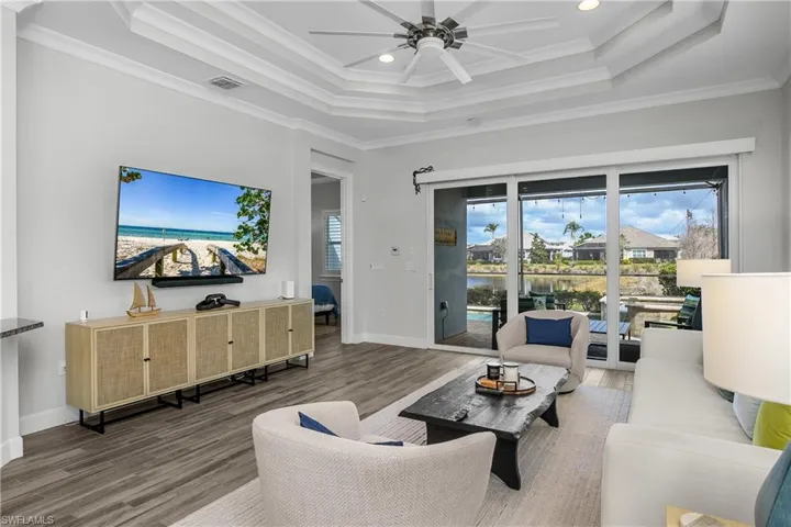 Great Room with Tray ceiling, fan, Tile Plank floors, recessed lighting, and crown molding
