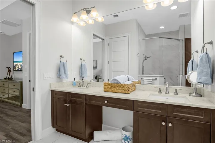 Owner's bath featuring double vanity and a marble finish shower