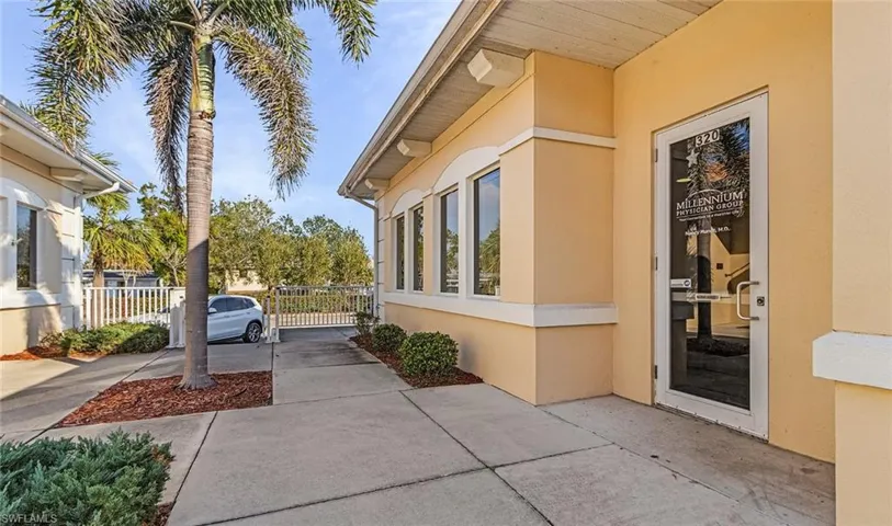 View of side of property featuring a gate, fence, and stucco siding