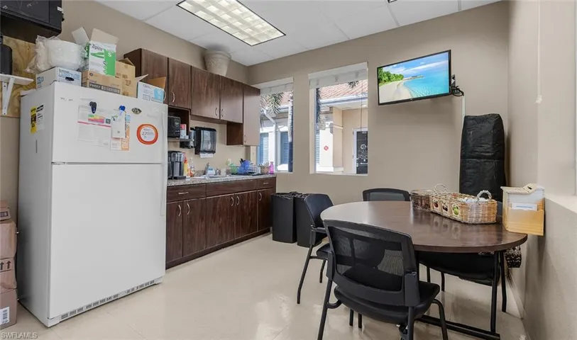 Kitchen featuring dark brown cabinetry, freestanding refrigerator, light countertops, a paneled ceiling, and light floors
