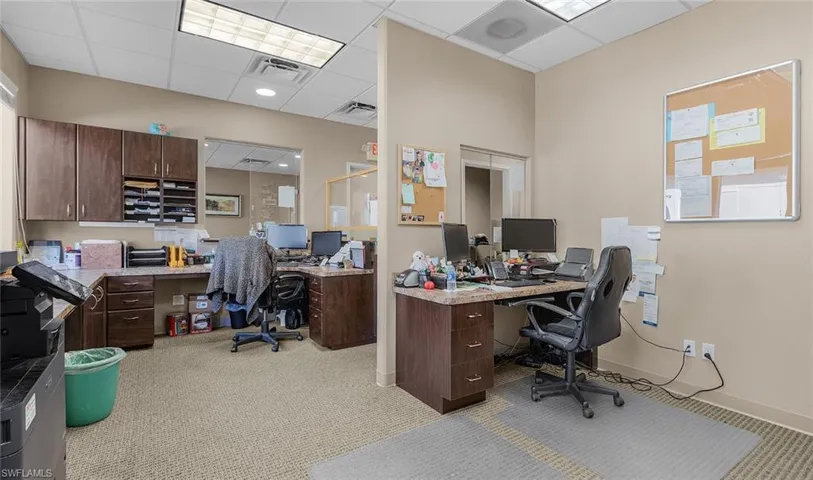 Office with a paneled ceiling, visible vents, and baseboards