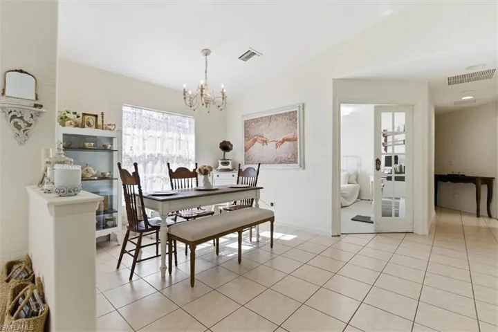 Dining room with a chandelier, light tile patterned floors, and vaulted ceiling