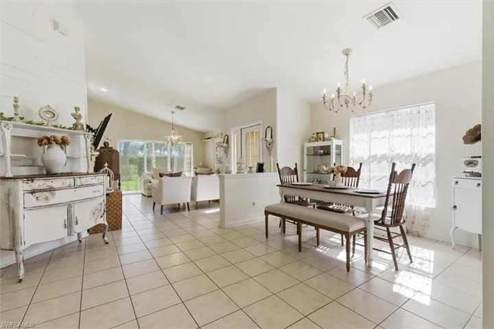 Dining area featuring a chandelier, vaulted ceiling, light tile patterned floors, and plenty of natural light