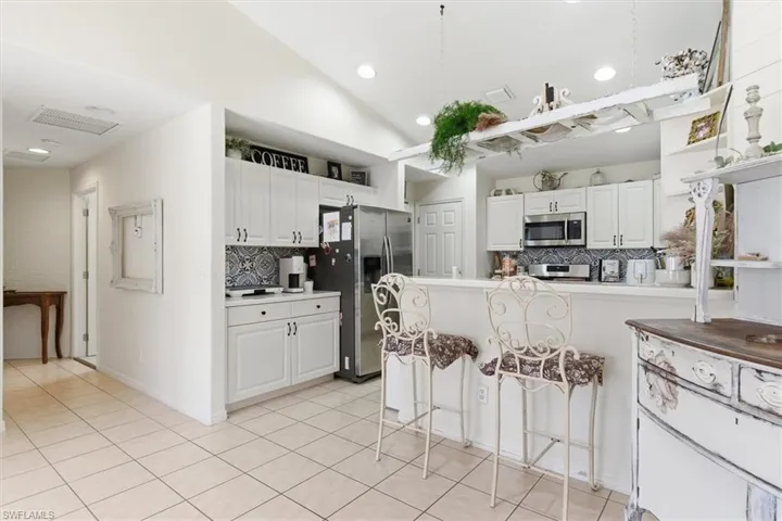 Kitchen with a peninsula, white cabinets, a breakfast bar, stainless steel appliances, and light countertops