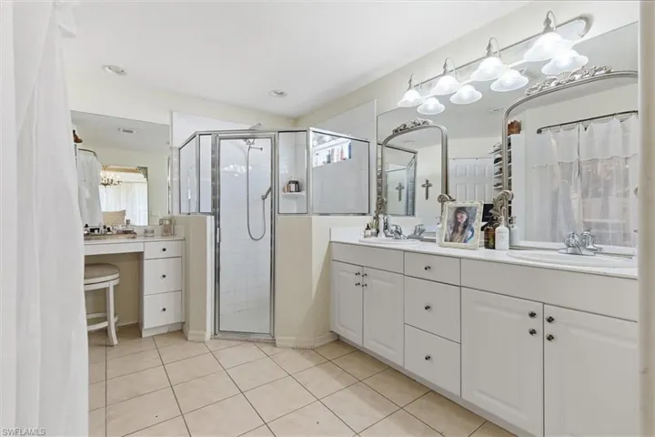Bathroom featuring double vanity, healthy amount of natural light, a stall shower, and light tile patterned flooring