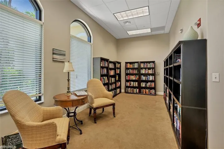 Sitting room featuring a towering ceiling, light carpet, and a drop ceiling