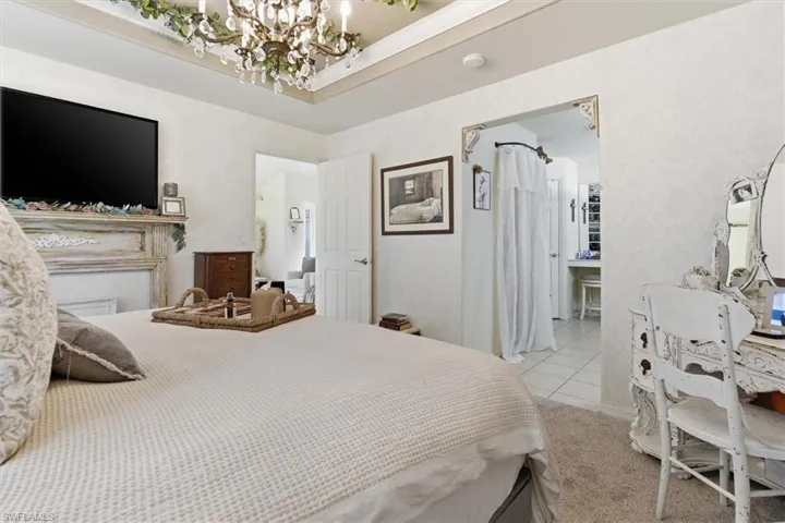 Bedroom featuring a chandelier, light tile patterned floors, and ensuite bathroom