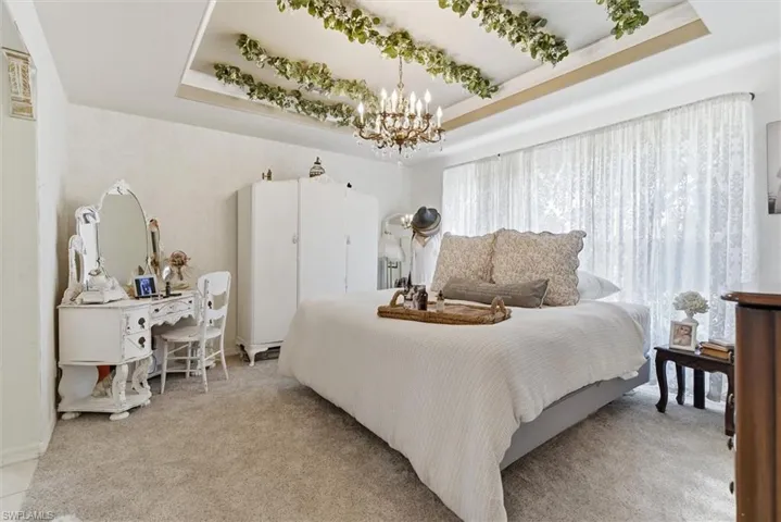Carpeted bedroom with a tray ceiling and a chandelier