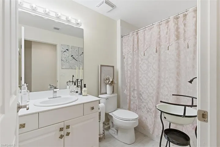 Full bathroom with curtained shower and vanity