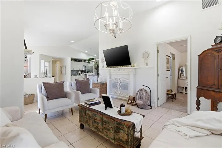 Living room featuring light tile patterned floors, recessed lighting, a chandelier, and high vaulted ceiling