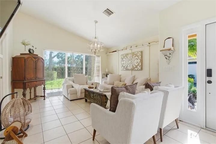 Living room with lofted ceiling, light tile patterned floors, and a chandelier