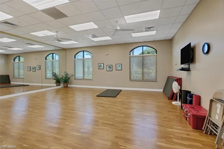 Workout area featuring light wood-type flooring, a drop ceiling, and ceiling fan