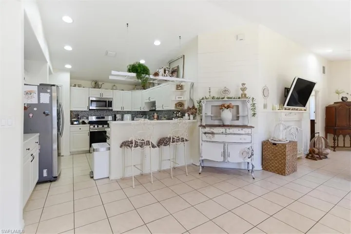 Kitchen with a breakfast bar, white cabinets, a peninsula, stainless steel appliances, and lofted ceiling