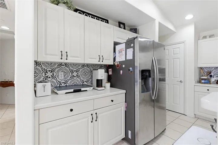 Kitchen featuring recessed lighting, backsplash, light tile patterned floors, light countertops, and stainless steel fridge