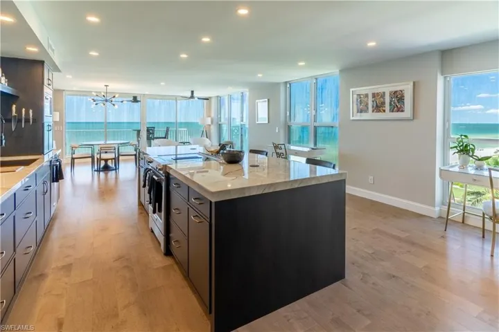 Kitchen featuring light stone counters, stainless steel electric stove, a spacious island, light wood-style flooring, and recessed lighting