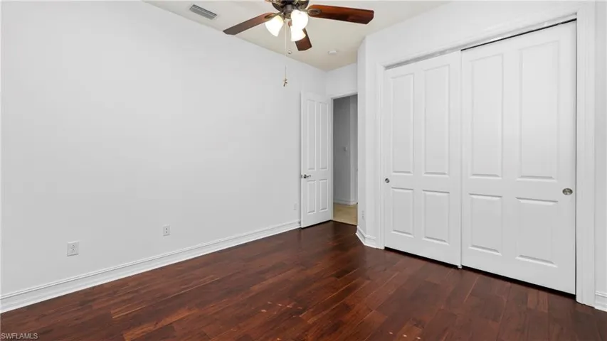 Unfurnished bedroom featuring dark wood-style flooring, a ceiling fan, and a closet