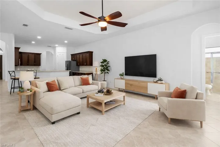 Virtually Staged Living area featuring arched walkways, a raised ceiling, a ceiling fan, and recessed lighting