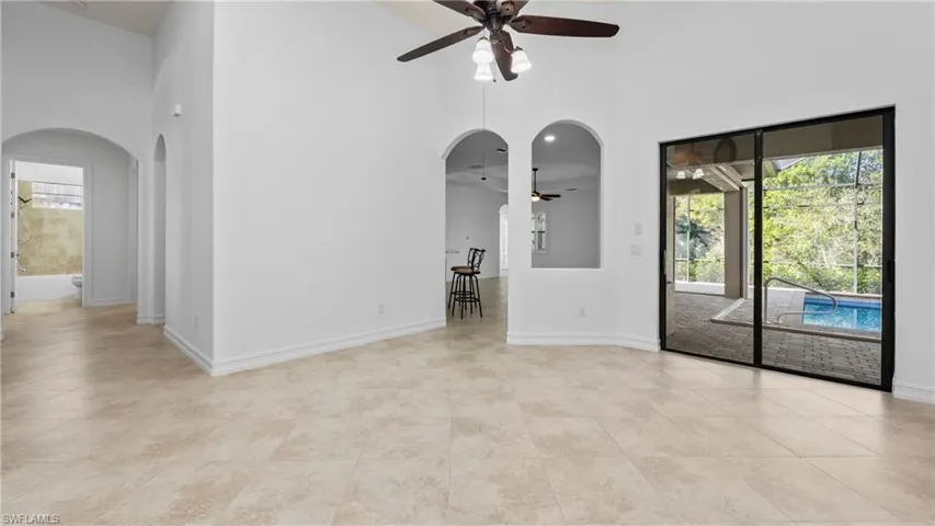 Spare room featuring arched walkways, ceiling fan, a high ceiling, and light tile patterned floors