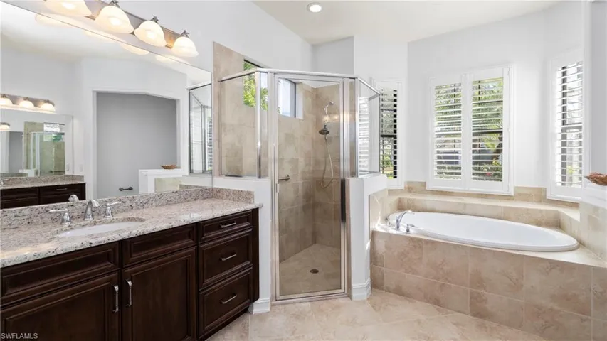 Bathroom featuring vanity, a stall shower, a garden tub, light tile patterned flooring, and recessed lighting