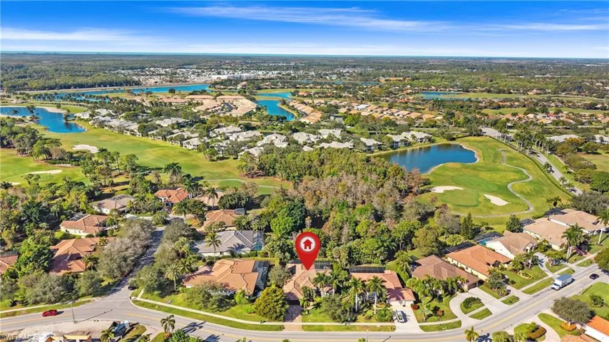 Aerial view of residential area featuring a golf course and a nearby body of water