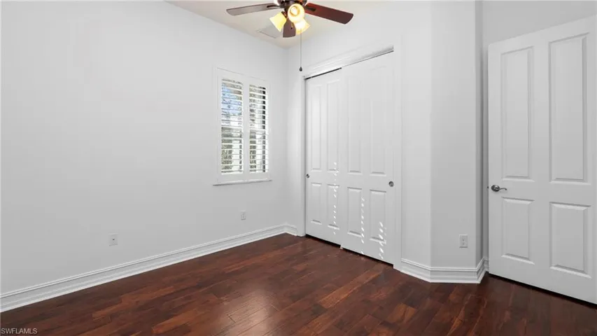 Unfurnished bedroom featuring dark wood-style floors, a closet, and a ceiling fan