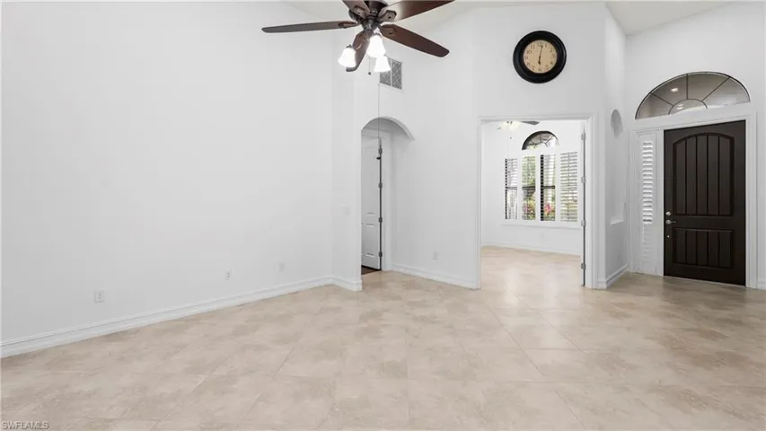 Entrance foyer with arched walkways, a ceiling fan, a high ceiling, and light tile patterned floors