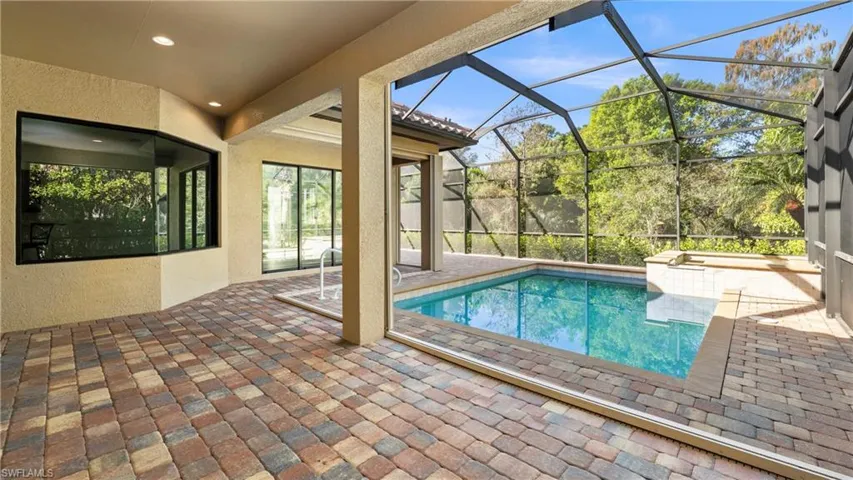 Swimming pool with a patio area, glass enclosure, and a sunroom