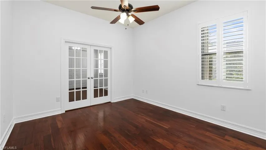 Spare room with french doors, a ceiling fan, and dark wood-style flooring