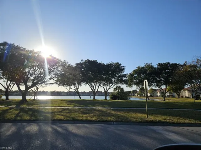 View of asphalt street featuring a water view and traffic signs